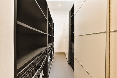 a long narrow hallway with black and white cabinets on either sides, leading to an open door that leads to another roomの写真素材