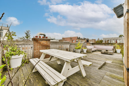 an outdoor area with wooden decking and white picnic tables in the photo is taken from the roof to the backyardの写真素材