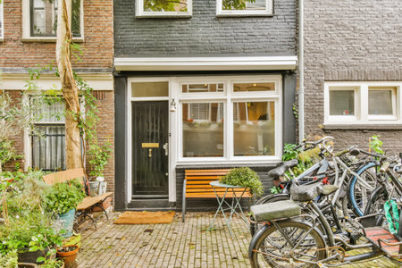 two bikes parked in front of a house on a cobbed street with potted plants and trees behind themの写真素材