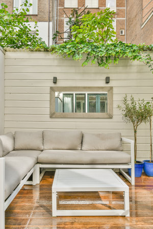 an outdoor living area with couches, coffee table and pots on the side of a building in the...