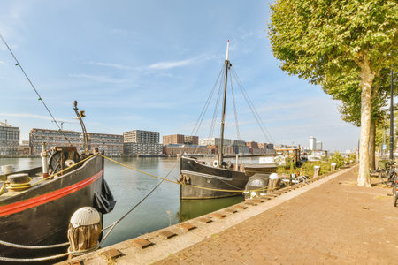 two boats docked in the water with buildings in the background and people walking on the sidewalk...