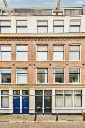 an old brick building in amsterdam, with blue doors on the front and windows open to let you into your homeの写真素材