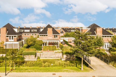 some houses in the middle of an area with green grass and trees on both sides there is a blue skyの写真素材