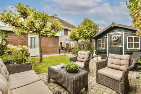 a backyard setting with chairs, tables and an umbrella over the patio area that has been used for several yearsの写真素材