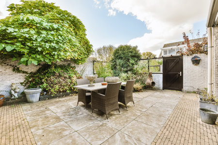 a patio with chairs, table and pots on the ground in front of a brick wall that has been painted...