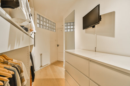 a closet with clothes hanging on the wall and a flat screen tv mounted over the door to the walk -...