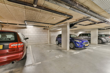 an underground parking area with cars parked in the space and two people standing on either side of each other vehiclesの写真素材
