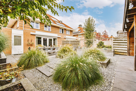 the back garden with gravel and plants in pots on the ground, surrounded by red brick house...