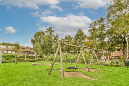an empty playground with swings and swing equipment in the fore - image is taken from above to show...