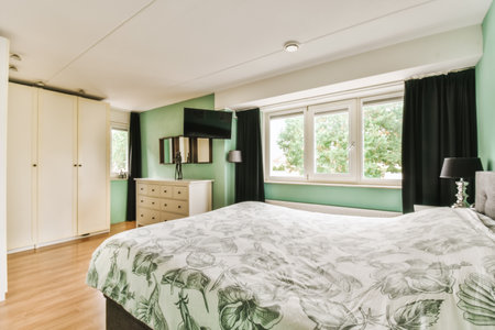 a bedroom with green walls and wood flooring in the middle of the room, there is a large bed