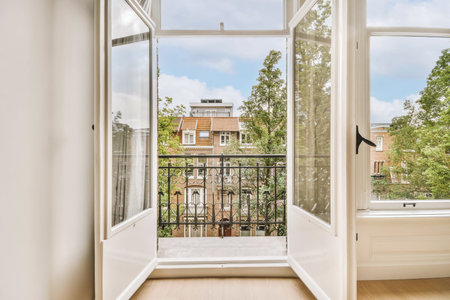 an open window looking out onto the street from a room with wooden floors and white walls, there is...