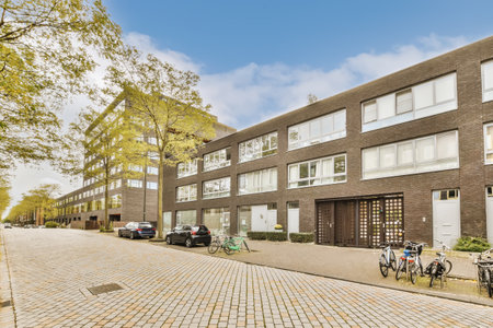 an apartment building with bicycles parked on the sidewalk in front of it and people walking down...