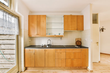 a kitchen with wood cabinets and black counter tops on the floor in front of an open window looking...