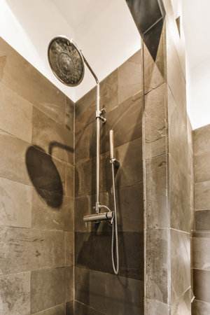 a shower with a clock on the wall next to it and water coming from the faucet in the showerの写真素材