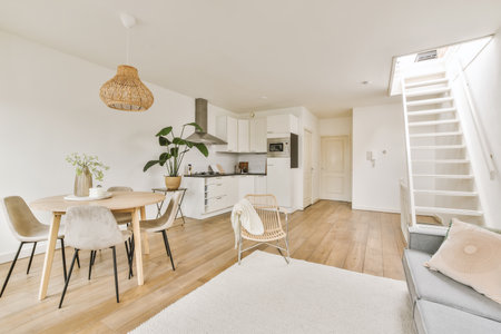 a living room with white walls and hardwood flooring, including a wooden dining table surrounded by...