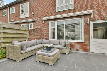 Amsterdam, Netherlands - 10 April, 2021: an outside living area with couches, tables and chairs on the patio in front of a brick building that has white shuttersのeditorial素材