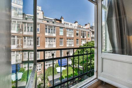 a balcony with buildings in the background and a view out to the street from an open window, taken...