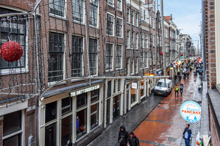 a city street with people walking on the sidewalks and cars parked in front of buildings that have been painted redのeditorial素材