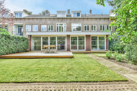 a house in the netherlands with green lawn and wooden decking, surrounded by lush greenes on a sunny dayのeditorial素材
