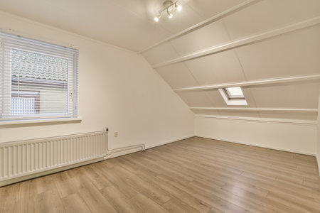 an empty room with white walls and wood flooring, there is a rad in the corner of the roomの写真素材