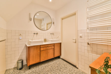 a bathroom with white tiles on the floor and wood cabinetd vanity in the corner, mirror is above itの写真素材