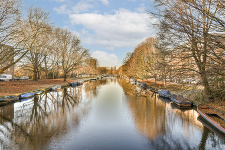 some boats in the water and trees on both sides with blue sky, white clouds and sun shining through themの写真素材