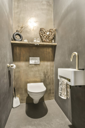 a bathroom with a toilet, sink and mirror on the wall next to it is an artistic sculpture that looks...