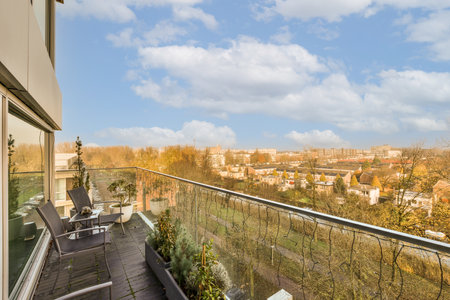 a balcony with some trees and buildings in the distance, as seen from an apartment window on a sunny dayの写真素材