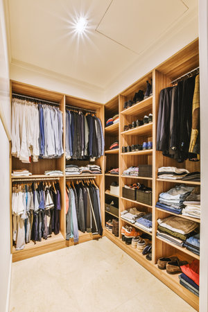 the inside of a walk - in closet with clothes and shoes hanging on wooden shelvings, showing how its organizedの写真素材