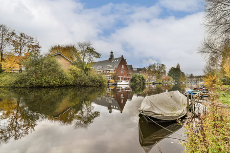 some boats in the water and houses on the other side of the river with blue sky above them, as seen from across theの写真素材