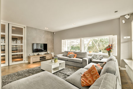 a living room with grey couches and white coffee table in the room is decorated with orange pillows on itの写真素材