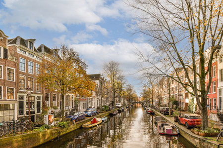 a canal with boats on the water and buildings in the background, taken from a boat tour through amsterdams canalsの写真素材