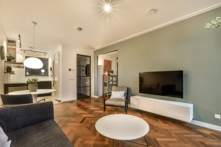 a living room with wood flooring and green walls in the center of the room is a large flat screen tv on the wallの写真素材