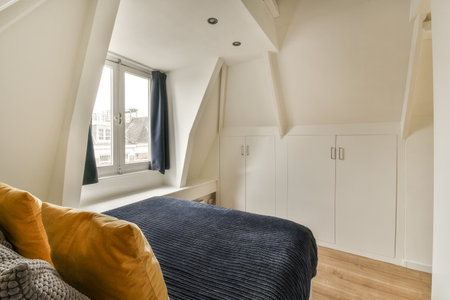 a bedroom with a bed and cupboards in the corner, next to a window that looks out onto the street