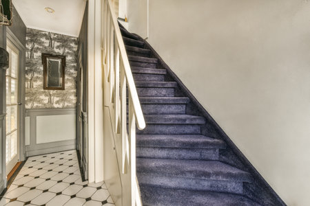 a hallway with blue carpet and white wallpaper on the walls there is a staircase leading up to the second floorの写真素材