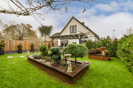 a backyard area with green grass and trees in the yard, including a birdbater sitting on a wooden...