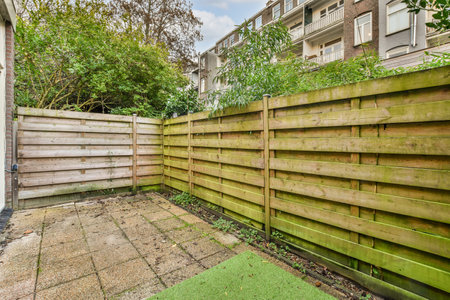 a backyard area with wooden fences and green grass in the yard is surrounded by trees, shrubs and...