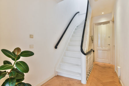 a white staircase with wood flooring and wooden handrails on the side of the stairs there is a plant...