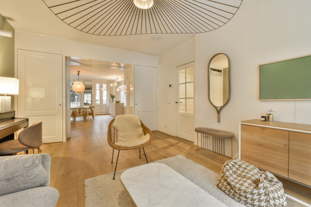 a living room with white walls and wood flooring there is a large mirror on the wall above the couch