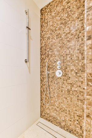a bathroom with tile on the walls and shower head mounted to the wall in front of the bathtub is visibleの写真素材