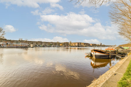 some boats in the water and buildings on the other side of the river with blue skies above them, as seen from across theの写真素材