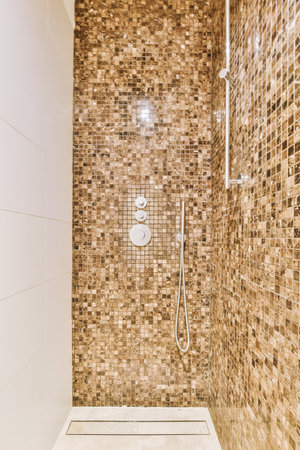 a walk in shower with brown and white tiles on the wall behind it is a glass door that leads to a toiletの写真素材
