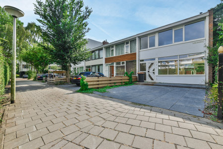 a house in the middle of an urban neighborhood with trees and plants growing on either side of the driveway areaの写真素材