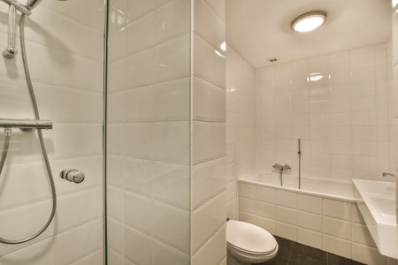 a modern bathroom with white tiles and black flooring the shower is next to the toilet in the corner...