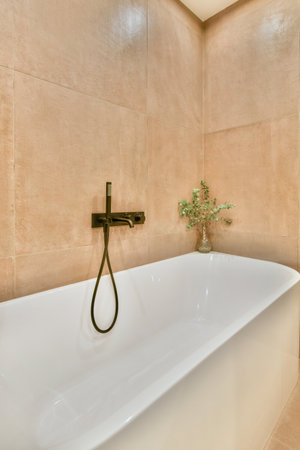 a white bathtub in the corner of a bathroom with a plant on its side and an open window