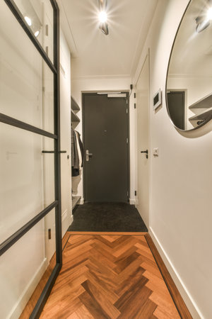a long narrow hallway with wood flooring and black trim around the door, leading to an open closet spaceの写真素材