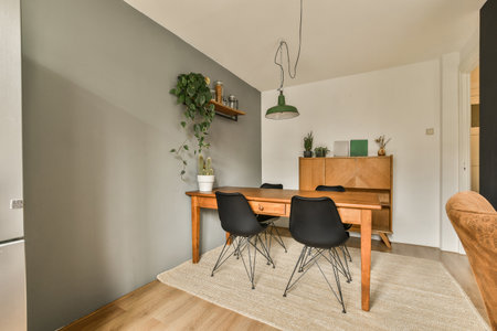 a dining room with two chairs and a wooden table in the center of the room, there is a plant hanging...