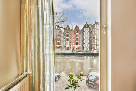 a view from the window of a room with a flower in it and buildings on the other side of the river