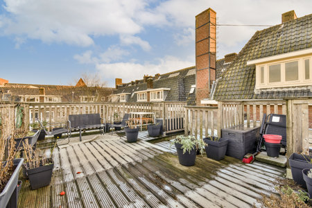 an outside area with wooden decking and potted planters on the ground in front of a row of houses