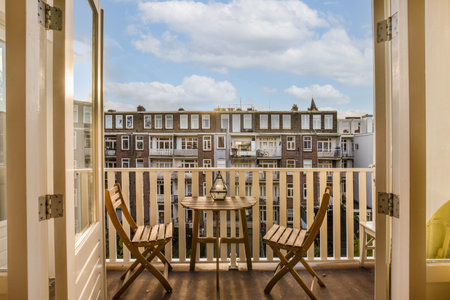 a balcony with two chairs and a table in front of the door that leads out to an outside patio areaの写真素材